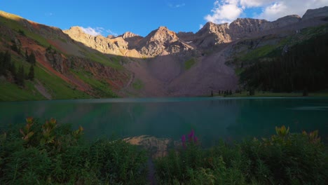 Lower-Blue-Lake-Mount-Sneffels-Wilderness-summer-sunset-golden-hour-Ridgway-Telluride-Colorado-wildflowers-shore-sunset-San-Juan-Rocky-Mountains-Uncompahgre-National-Forest-clear-sky-clouds-pan-right