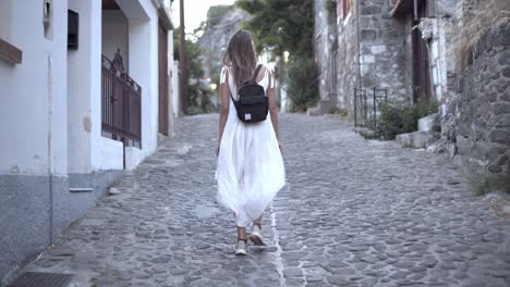 solo-female-traveler-walks-the-safe-cobblestone-back-streets-on-the-island-of-Lesvos,-Greece-near-dusk