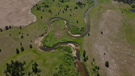 Aerial-high-angle-overview-of-meandering-winding-rivers-and-green-plains-in-the-Big-Sandy-Trailhead-of-Wind-River-Wilderness,-Wyoming,-with-mountain-views