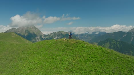 Couple-enjoying-breathtaking-mountain-view-on-green-hill,-Austria,-captured-by-drone-360-shot