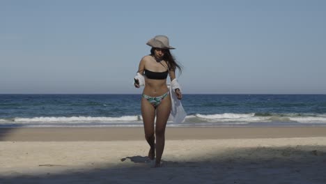 Beautiful-girl-at-beach-in-bikini-swimsuit-walking-on-sand,-ocean-background