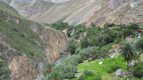 Aerial-follows-Rio-Colca-past-lush-green-oasis-of-Sangalle-in-Peru