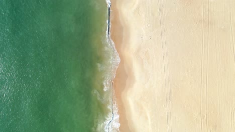 Elevated-view-of-green-ocean-surf-crashing-on-golden-beach