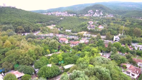 Aerial-view-of-a-hill-with-trees-and-houses-near-a-street-by-drone