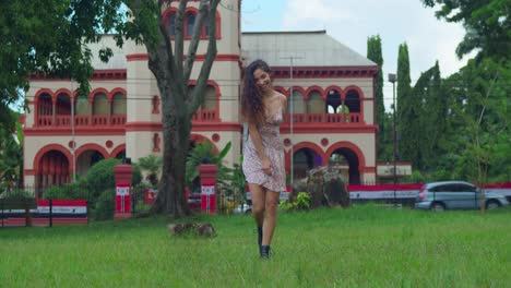 Young-curly-hair-girl-enjoy-playing-in-an-open-field-in-a-mini-dress-and-boots-with-a-castle-in-the-background