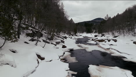 Aerial-scenic-drone-up-motion-Canadian-wilderness-mid-winter-near-north-Quebec-Stoneham-Ski-Resort-of-frozen-over-Sautaurski-River-upstream