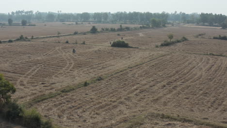 Aerial-of-motorcyclists-going-through-harvested-fields-in-Cambodia