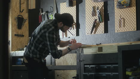 Junger-Tischler-Arbeitet-In-Seinem-Atelier-An-Einem-Holzprojekt,-Seitenansicht