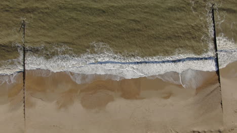 Aerial-up-motion-ooking-down-peaceful-golden-colored-beach-from-with-waves-crashing-Bournemouth-UK-English-Channel-surf-Pacific-Ocean