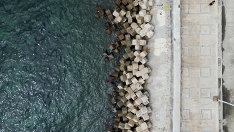 Birdseye-view-of-shoreline-with-erosion-control-concrete-blocks,-stairs-enter-to-ocean