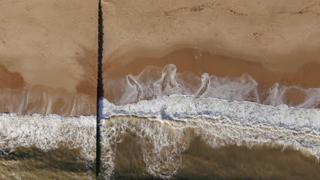 Aerial-looking-down-to-the-right-motion-peaceful-golden-colored-beach-from-with-waves-crashing-Bournemouth-UK-English-Channel-surf-Pacific-Ocean