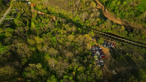 Aerial-view-of-junk-yard-in-with-stacks-of-used-cars-in-wooded-area-in-Fayetteville,-Arkansas,-USA