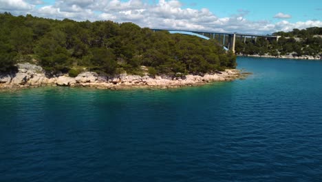 4K-slow-tracking-shot-along-a-coastline,-revealing-Morinje-Bridge,-Croatia