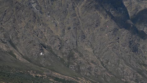 Small-plane-and-helicopter-crossing-flight-paths-in-front-of-massive-mountain-range