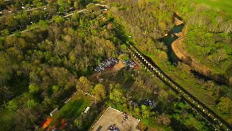 Aerial-view-of-junk-yard-in-with-stacks-of-used-cars-in-wooded-area-in-Fayetteville,-Arkansas,-USA
