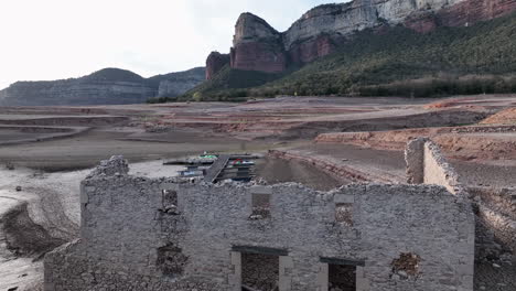 Old-buildings-emerged-from-swampy-waters-of-Sau-Basin-during-dry-season,-Catalonia-in-Spain