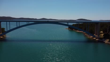 4K-fast-tracking-shot,-gradually-lowering-and-moving-under-Morinje-Bridge,-Croatia