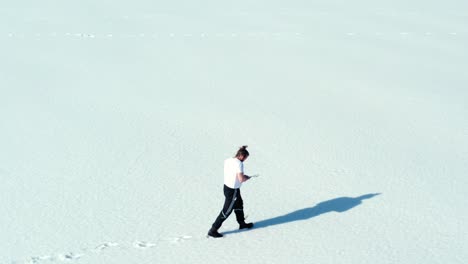 Aerial-View-Of-A-Lone-Man-Walking-Through-Snow-Leaving-Foot-Marks