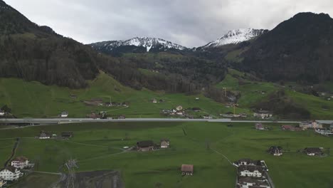 Hyperlapse-Aus-Der-Luft,-Verkehr-Auf-Der-Straße-Und-Grüne-Landschaft-Der-Schweizer-Alpen,-Drohnenaufnahme