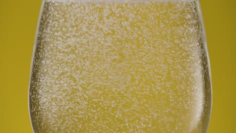 Extreme-close-up-of-a-glas-with-sparkling-water-isolated-on-yellow-background