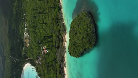 Kanumera-Bay-on-the-Isle-of-Pines-with-a-view-of-the-Sacred-Rock-islet---aerial-in-vertical-orientation