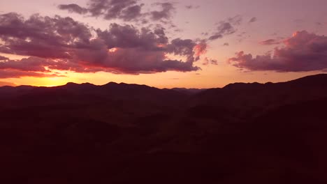 Beautiful-pink-sky-and-clouds,-aerial-shot-of-hills-in-sunset