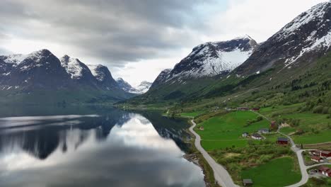 Oppstrynsvatnet-lake-close-to-mountains-containing-the-Jostedal-Glacier---Downward-moving-summer-aerial-with-mountain-reflections-in-the-lake---Road-RV-15-leading-to-Strynefjell-mountain-crossing