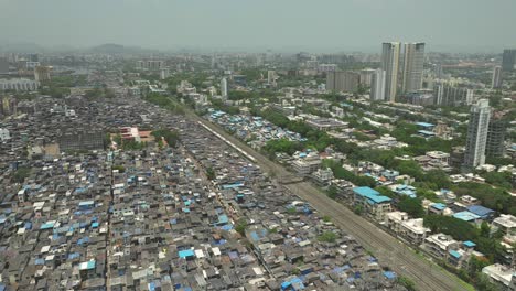 Aerial-static-shot-of-train-passing-next-to-the-Dharavi-slum-in-Mumbai,-India