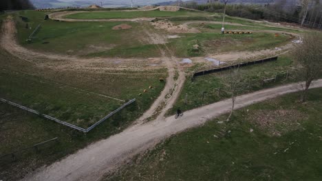 Aerial-shot-of-a-motocross-track-with-a-boy-riding-his-bike-around-it