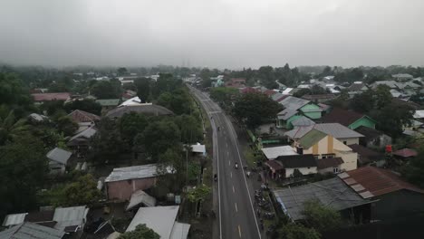 Low-cloud-and-mist-in-wet-Lombok-village,-aerial-flight-over-highway