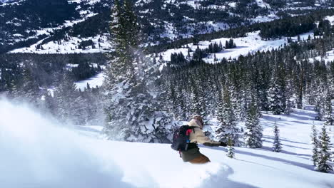 Male-Snowboarder-riding-down-fresh-powder-snow-followed-blue-sky-steep-turns-Vail-Pass-Colorado