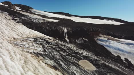 Luftlandschaftsansicht-Eines-Gletscherflusses,-Der-An-Einem-Sonnigen-Tag-Einen-Wasserfall-Vor-Einem-Isländischen-Gletscher-Hinunterfließt