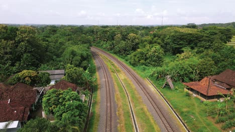 Drone-following-curve-in-train-track-travelling-through-countryside,-Indonesia