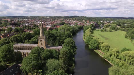 Aerial-view-dolly-across-Holy-Trinity-church-and-river-Avon-quiet-suburban-Warwickshire-landscape