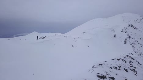 Ein-Einsamer-Bergsteiger-Geht-Auf-Dem-Bergrücken-Zum-Schneebedeckten-Gipfel