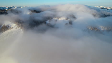 Vista-Aérea-De-Las-Nubes-Sobre-Las-Colinas-Nevadas-Y-Los-Picos-De-La-Cordillera-Teton,-Wyoming-Usa-En-El-Soleado-Día-De-Invierno