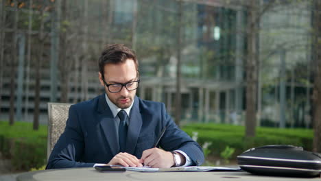 Thoughtful-Adult-Man-In-Suit-Working-Outdoors-in-A-Park,-Business-Person-Writing-Inspiration-Notes-and-Creative-Ideas-on-Paper