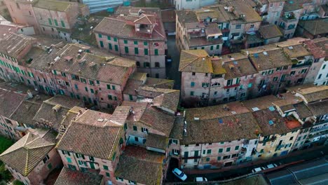 Aerial-over-traditional-urban-housing-towards-the-Duomo-di-Siena-in-Siena,-Province-of-Siena,-Italy