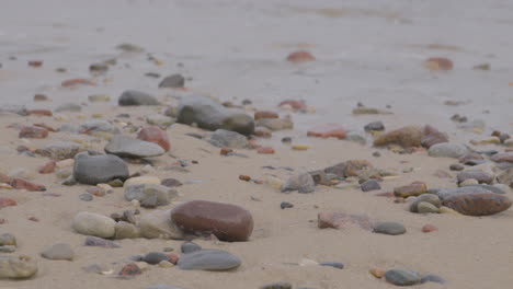 Am-Sandstrand-Liegen-Verstreute-Steine-Unterschiedlicher-Größe-Entlang-Der-Meeresküste