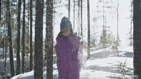 Slow-motion-of-happy-girl-playing-with-snow-in-woods-on-bright-day