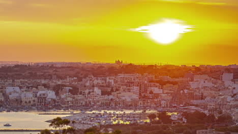 Vast-landscape-of-city-and-nature-during-glowing-sunset-in-Malta,-time-lapse-view