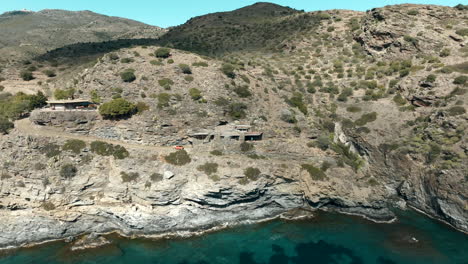 Luxury-house-on-rocky-cliff-near-lake-water-in-Spain,-aerial-drone-view