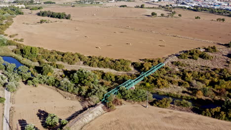 Establish-brown-farmland-with-a-remote-and-abandoned-railway-bridge,-aerial