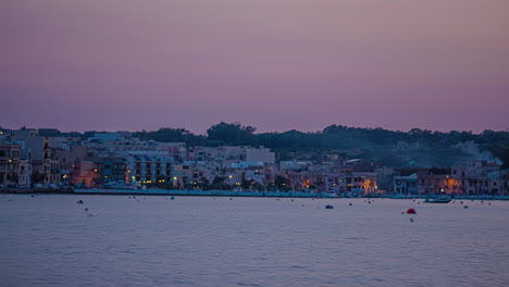 Sunset,-lights-come-on-in-the-houses-of-the-small-town-of-Marsaxlokk-in-Malta