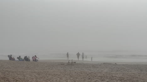 Children-swimming-and-playing-in-ocean-on-foggy-morning-at-beach-as-parents-watch