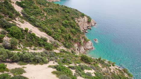 Top-Down-View-Over-A-Rocky-Seaside,-Turquoise-Water,-Lush-Vegetation,-Fari-Beach,-Thassos-Island,-Greece