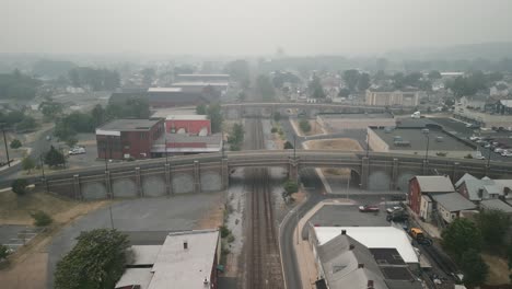 Aerial-drone-view-of-vehicles-passing-over-railroad-bridge-in-thick-haze-and-smog