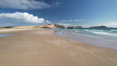 Einsamer-Mann,-Der-Am-Wunderschönen-Sandstrand-Te-Werahi-Spaziert,-Atemberaubende-Naturlandschaft-Neuseelands---Luftdrohne