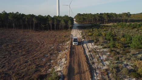 white-van-driving-along-a-sandy-farm-road-in-Nazare-with-tall-trees-lining-the-road-and-a-windmill-in-the-background