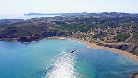 Vista-Aérea-De-La-Playa-De-Cavalleria-En-Menorca-Con-Sol-Brillando-A-Lo-Largo-De-La-Costa